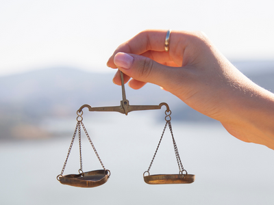 Water Balancing Scale Image of a hand holding a balanced scale with water in the background.