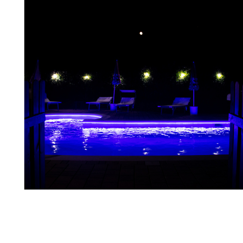 Pool Lit Up at Night Outdoor pool lit up at night by various lights both purple and warm white.