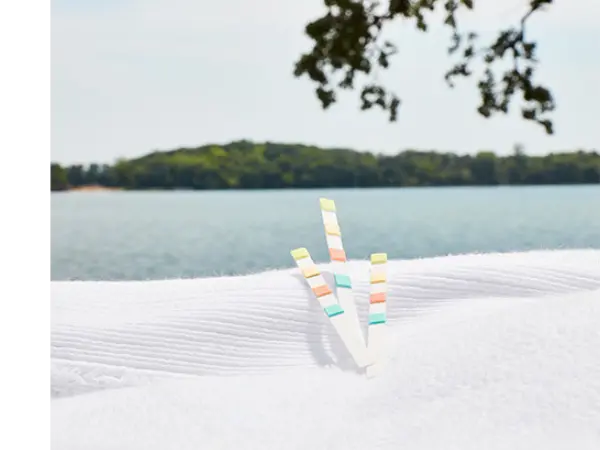 3 colored test strips sitting on a white towel in front of a lake