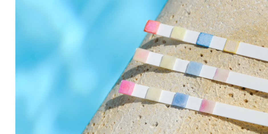 Three colored test strips sitting on the edge of a pool