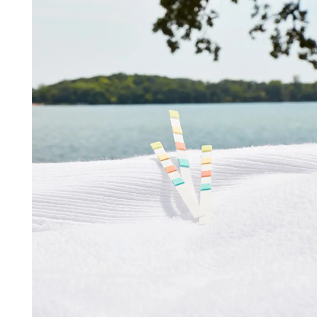 FROG Test Strips sitting on the edge of a hot tub on top of a white towel with a lake scene in the background.