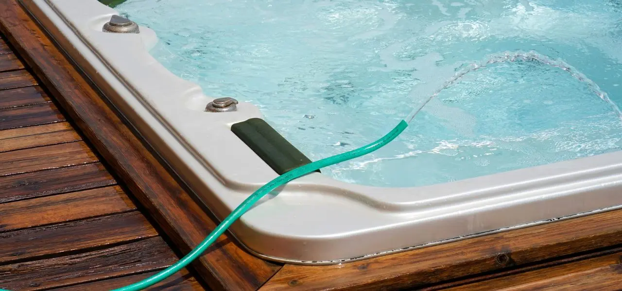 In-ground hot tub with a hose over it refilling it.