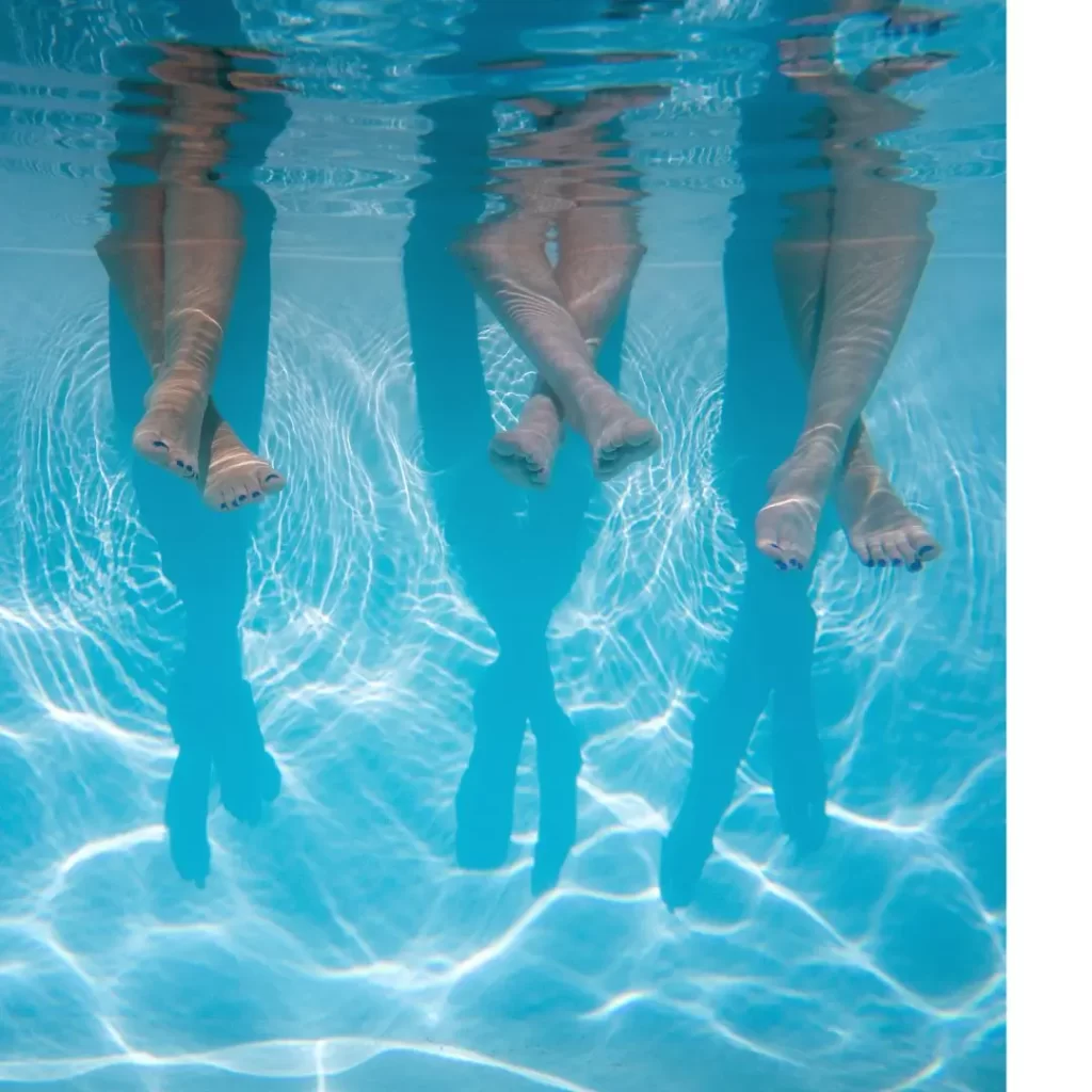 three kids sit next to each other in this underwater pool shot.