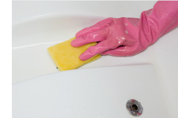 A gloved hand with a sponge wiping the surfaces of a hot tub.