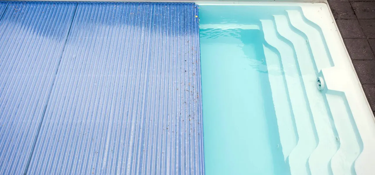 A pool cover being pulled over an outdoor pool