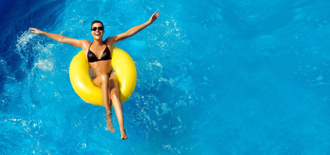 Young woman lays on a yellow floatie with her arms stretched out
