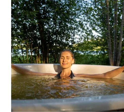 A woman sits in the hot tub with her arms outstretched on the edge of the hot tub.