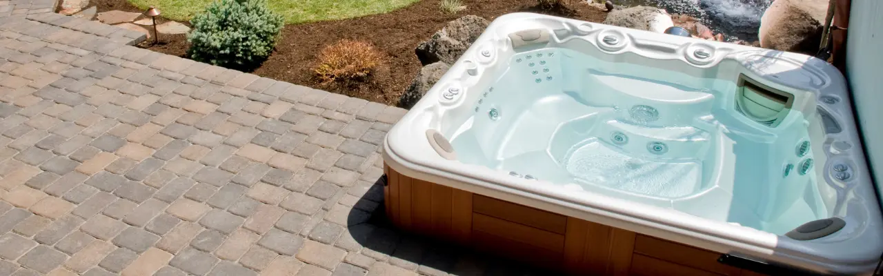 Overhear shot of anm outdoor hot tub that sits on a cobblestone patio