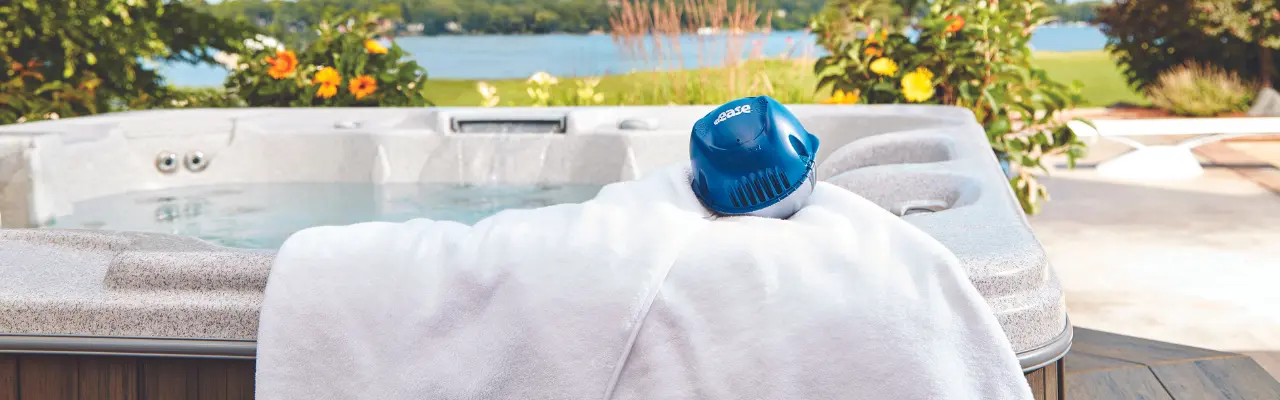 A FROG @ease Floating System sits on a white towel on the edge os an outdoor hot tub.