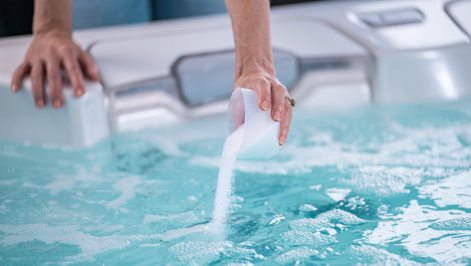 FROG® @ease® Target being poured from a TruDose™ cap into a clear hot tub for precise sanitizer dosing.