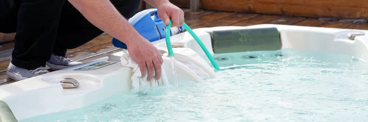 Use Before a Drain and Refill — For a Cleaner, Fresher Hot Tub Every Time Hot tub being scrubbed with a towel and rinsed with a hose — cleaning before drain and refill or seasonal shutdown.