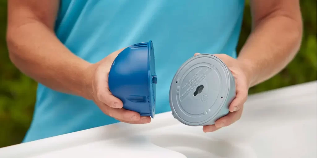 Person holding both parts of the FROG @ease® System, showing its dual-action sanitizing design for hot tubs.