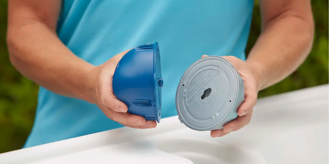 Person holding both parts of the FROG @ease® System, showing its dual-action sanitizing design for hot tubs.